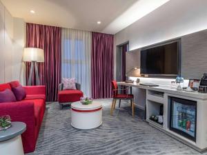 海防海丰美居酒店的酒店客房设有红色的沙发和电视。