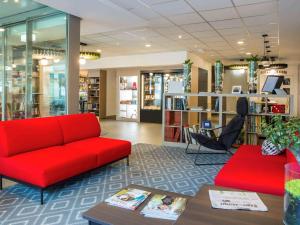 洛桑洛桑中心宜必思酒店的一个带红色沙发和桌子的图书馆