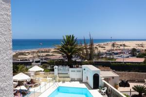 英格兰海滩Primera linea de Playa del Ingles y las Dunas de Maspalomas的享有海滩美景的度假酒店设有游泳池