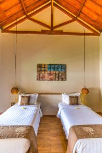 龙目岛库塔Nativo Lombok Hotel的配有木天花板的客房设有两张床。