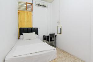 巴东Lestari Guesthouse的一间卧室配有一张白色的床和黑色床头板