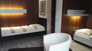 萨尔布吕肯Hotel Römerhof的一间设有两张床和椅子的房间