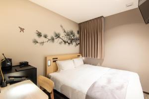 东京东京新宿歌舞伎町柔婕阁酒店的酒店客房配有一张床、一张桌子和一把椅子。