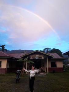 姆鲁Mulu D cave homestay的站在一座有彩虹的房子前面的女人