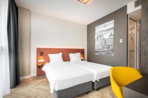 阿姆斯特丹Hotel New Kit的一间卧室配有一张大床和一张黄色椅子