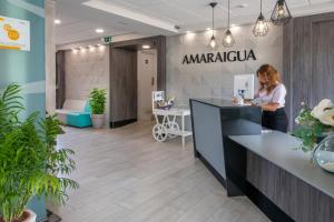 马尔格莱特德玛Hotel Amaraigua – All Inclusive – Adults Only的一名妇女站在阿玛尔玛办公室的柜台