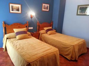 别尔萨Hostal Restaurante Asador Pañart的蓝色墙壁客房的两张床