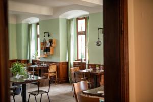萨勒河畔巴特诺伊施塔特拜德纽斯塔德特城堡酒店的一间设有桌椅的餐厅,位于带绿色墙壁的房间内