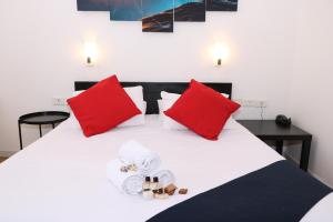 阿拉德因巴尔酒店的一张带红色枕头的白色床和毛巾