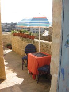 沙拉400YR Farmhouse in Xaghra Gozo - Separate Rooms的阳台配有带2把椅子和遮阳伞的桌子