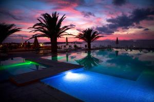 埃斯普霍斯桑威蓬塔俱乐部高级酒店的棕榈树和日落的游泳池