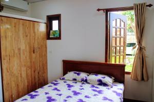 Ấp Mỹ AnCocoPalm Villa near Beach - Palm Room的一间卧室配有一张带紫色和白色床单的床和窗户。