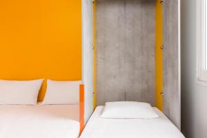 贝诺斯特ibis budget Lyon Est Beynost的橙色墙壁的客房内的两张床