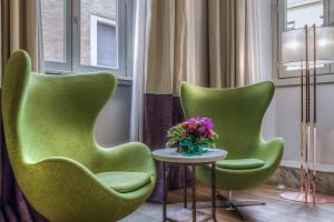 罗马马尔蒂斯宫殿酒店的两把绿椅,坐在桌子旁,花瓶
