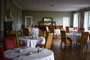 Strachur克里甘斯酒店的用餐室配有桌椅和白色的桌布