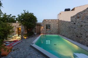 皮吉Muazzo Creta Stone House, a Fairytale Cottage, By ThinkVilla的石头建筑前的游泳池