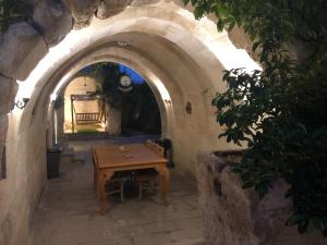 于尔居普Kayhan Cave Villa的石砌建筑中带木桌的拱门