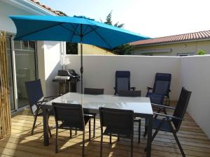 安德诺莱斯贝恩Villa du Cabestan的庭院内一张桌子和椅子,上面摆放着蓝色的遮阳伞