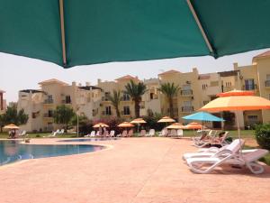萨伊迪耶TRIPLEX LA MARINA SAIDIA的毗邻度假酒店的带椅子和遮阳伞的游泳池