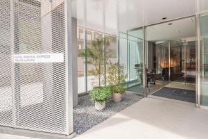 东京Hotel Oriental Express Tokyo Kamata的玻璃门和盆栽植物的建筑物入口