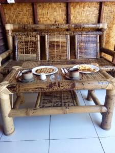 龙目岛库塔Bale Hostel的一张木桌,上面放着食物盘