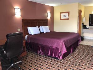 IndianolaAmericas Best Value Inn-Indianola的配有一张床和一把椅子的酒店客房