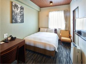 福冈One's Hotel Fukuoka的小酒店客房配有一张床和一张书桌