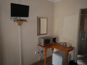 UlundiMarietjies Guesthouse的客房设有电视和带微波炉的桌子。
