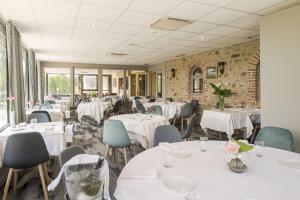 埃夫龙马鞍浅滩客栈的餐厅设有白色的桌椅和窗户。