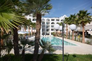 托尔托雷托Residence La Villa的一个带游泳池和棕榈树的度假村