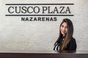 库斯科Cusco Plaza Nazarenas的坐在标志前面桌子上的女人