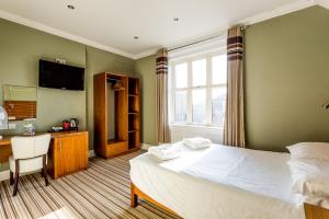 切斯特堡恩洛奇酒店的一间卧室配有一张床、一张书桌和一个窗户。