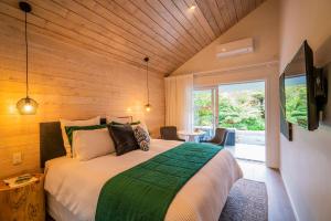 怀蒂昂格Wairua Lodge - Rainforest River Retreat的一间卧室设有一张带木制天花板的大床