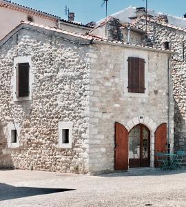 吕奥姆Ruoms Petite Maison 3* centre-village的一座古老的石头建筑,设有木门和一座建筑