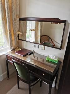 坎伯利Hatsue Guest House的一张带镜子的桌子和一把绿色椅子
