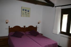 OncalaHotel Rural San Millán的卧室内的紫色床,带窗户