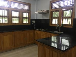 KilinochchiAhi House的厨房配有木制橱柜和黑色台面