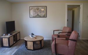 莱米尔Het Friese Landschap的客厅配有电视、2把椅子和1张桌子