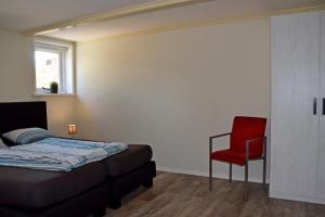 莱米尔Het Friese Landschap的一间卧室配有一张床和一张红色椅子