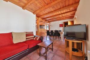 SoultzerenLe Chalet du Tanet spa sauna terrasse en Alsace的客厅配有红色沙发和平面电视