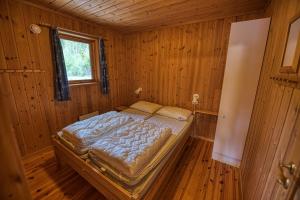 弗罗达尔Vrådal Hyttegrend的木制客房内的一间卧室,配有一张床