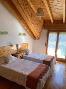 贝尔维尔德赛当亚Ático con encanto en Bellver de Cerdanya的客房设有两张床铺、木制天花板和窗户。