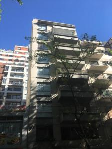 布宜诺斯艾利斯Studio Palermo La Rural y Embajada USA的一座高大的白色建筑,前面有一棵树
