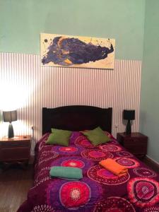 蒙得维的亚El secreto Casa Art的一间卧室配有一张带紫色毯子和绿色枕头的床。