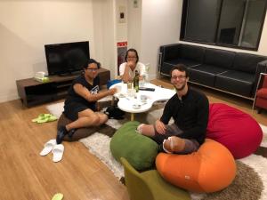 名古屋Guesthouse TOHO的一群三人坐在客厅周围