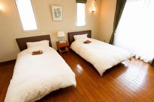 浦安Urayasu Guesthouse 浦安ゲストハウス的两张睡床彼此相邻,位于一个房间里