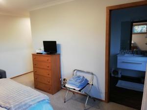 基督城Whaka Heights的一间卧室配有一张床和一个带水槽的梳妆台