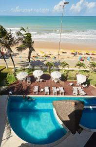 纳塔尔Elegance Hotel Natal Beira Mar的海滩旁的游泳池,配有椅子和遮阳伞
