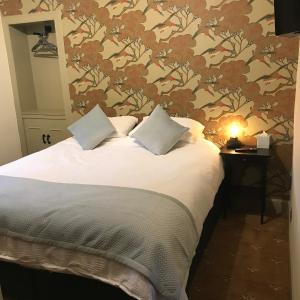 福尔柯克The Victoria Inn Blythswood Snug的一间卧室配有一张带花卉壁纸的床
