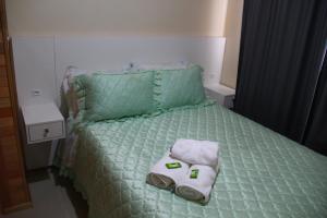 圣若阿金Apartamento Serrano的一张带绿色棉被和毛巾的床